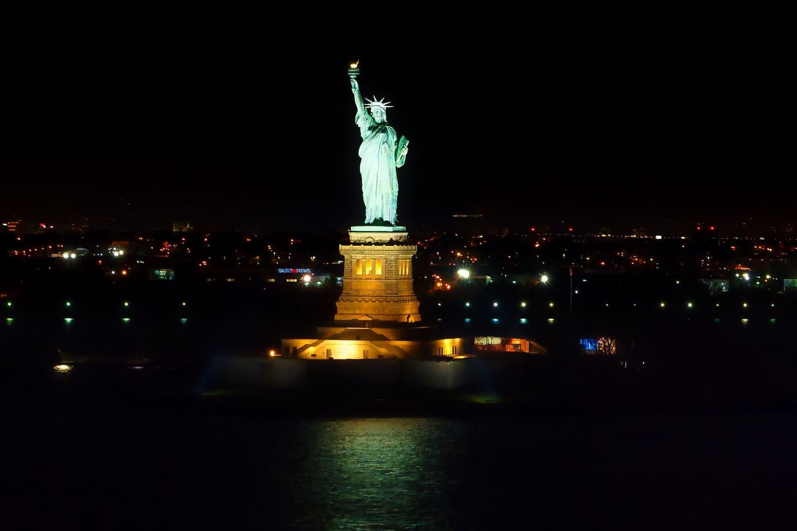 The Statue of Liberty illuminated in New York Harbor at night