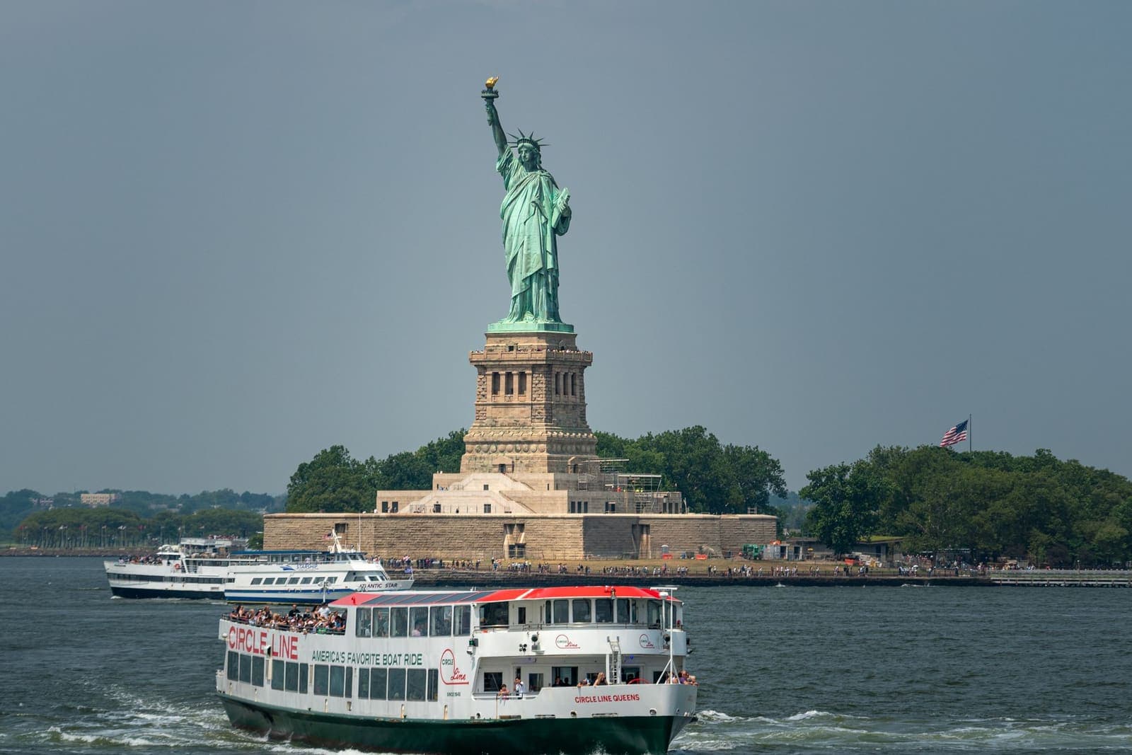 A sightseeing boat passing the Statue of Liberty in New York Harbor