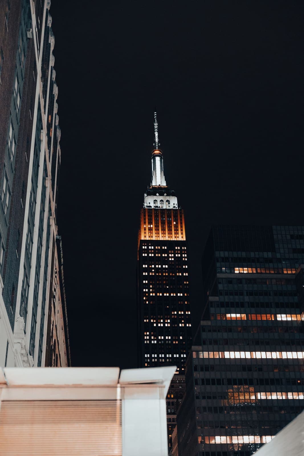 The Empire State Building spire glowing against a dark sky