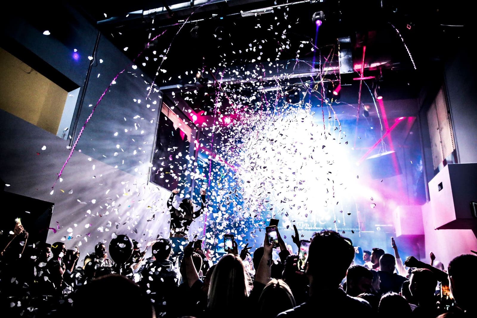 Confetti bursting over a crowd in front of a lit stage